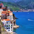 buildings on the coast with beautiful blue water and green mountains